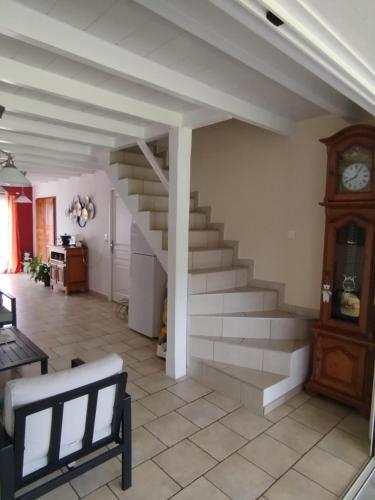 a living room with a staircase and a clock at Le champ Vert in Chamblanc