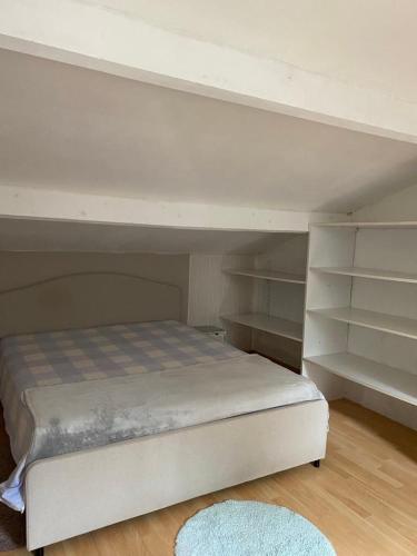 Ce lit superposé blanc se trouve dans un dortoir doté d'étagères. dans l'établissement Grande chambre 25m - CLIM, à Castelnau-le-Lez