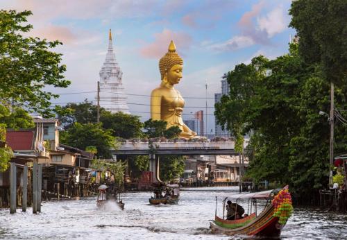 a boat in a river in front of a giant golden statue at Do Dee cafe in Bangkok