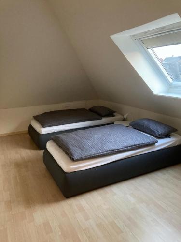 two beds in a attic room with a window at Gästewohnung 25 in Wildeshausen