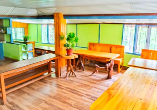 Habitación con mesa de madera, bancos y paredes verdes. en Sikkim Silk Route Riverside Resort, Rongli, en Rongli
