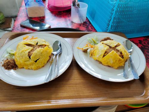 two plates of food on a tray with spoons at Harmony Resto&Homestay in Lambangkuning
