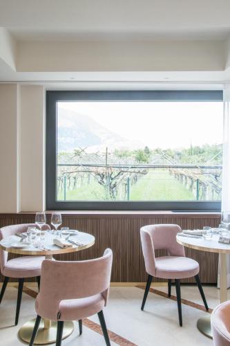a restaurant with two tables and chairs and a large window at Villa Nicolli Romantic Spa Resort - Adults Only in Riva del Garda