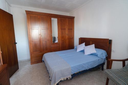 a bedroom with a blue bed and a wooden cabinet at Vivienda Unifamiliar 500 m cuadrados in Isla Cristina