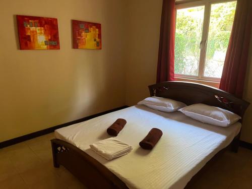 a bed with two slippers on it with a window at Kalan Digana (Kandy) in Digana