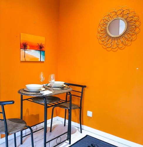 une salle à manger aux murs orange avec une table et des chaises dans l'établissement Studio 28m2 avec balcon, très proche de la mer, à Saint-Laurent-du-Var