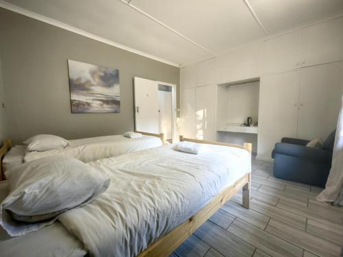 a bedroom with two beds and a blue couch at Mitchell Guesthouse in Pietermaritzburg