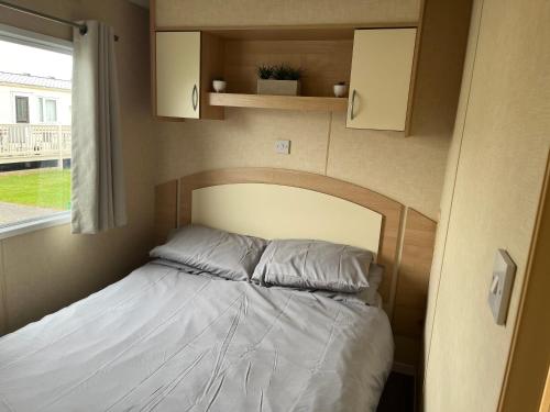 a bed in a small room with a window at Dog Friendly Lovely Caravan 4 Berth Towyn North Wales Read full host details before booking Mon in to Fri out Fri in to Mon out Mon to Mon Fri to Fri ONLY in Abergele