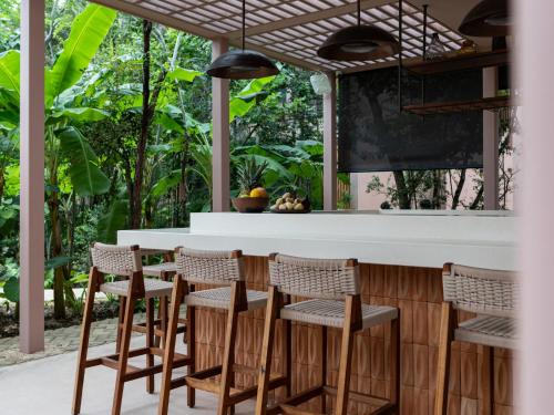 a kitchen with a bar with rattan chairs at Aflora Tulum - Managed by Elite Alliance in Tulum