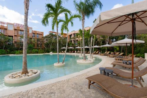 a pool at a resort with chairs and umbrellas at Aflora Tulum - Managed by Elite Alliance in Tulum