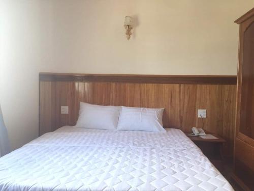 a bedroom with a bed with a wooden head board at Kbang in De Dang (1)
