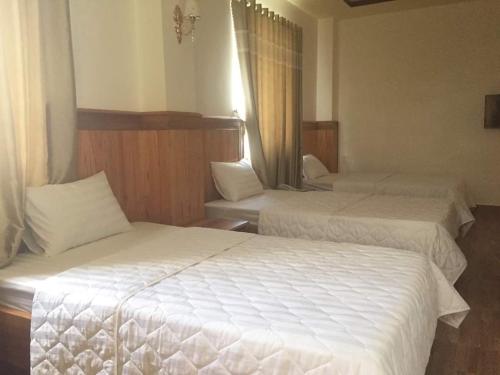 a hotel room with two beds with white sheets at Kbang in De Dang (1)