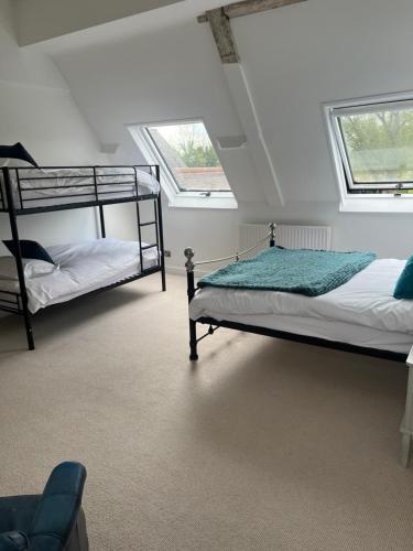 two bunk beds in a room with two windows at The Rutland House South Luffenham in Oakham