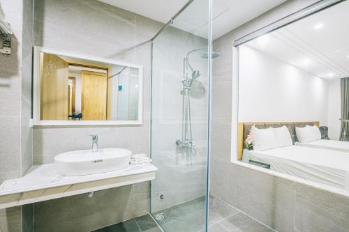 a bathroom with a sink and a shower and a bed at Khách Sạn Sen Biển - FLC Sầm Sơn in Sầm Sơn