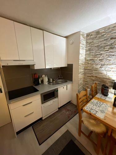 a kitchen with white cabinets and a dining room table at Cosy 2 pièces proche Châtel in Abondance