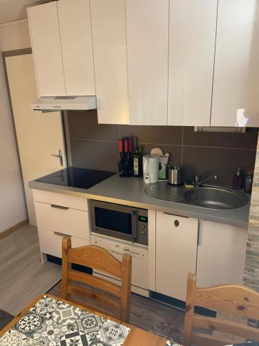 une cuisine avec des armoires blanches et un évier dans l'établissement Cosy 2 pièces proche Châtel, à Abondance