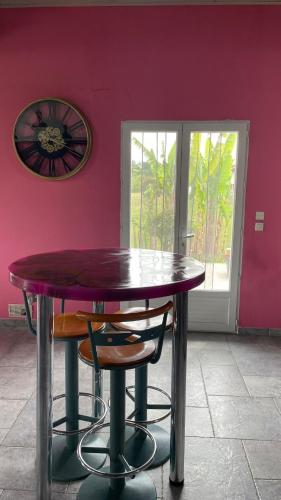 a table and chairs in a room with a pink wall at Chambre 2 couchages proche du bourg de La Bastide Clairence in Hasparren