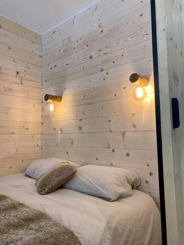 un lit dans une chambre avec un mur en bois dans l'établissement Appartement au pied des pistes à Chantemerle, à Saint-Chaffrey