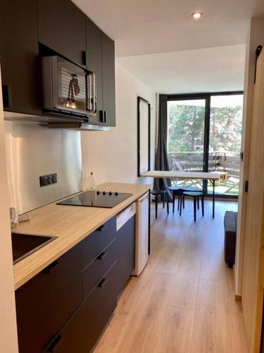 une cuisine avec des armoires noires et une table avec vue dans l'établissement Appartement au pied des pistes à Chantemerle, à Saint-Chaffrey