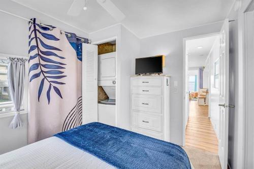 a white bedroom with a bed and a tv at Sea La Vie Beach Cottage in Virginia Beach
