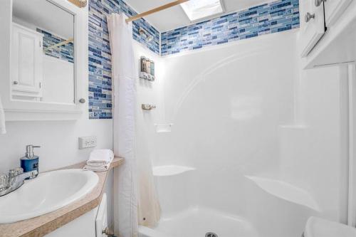 Baño blanco con lavabo y espejo en Sea La Vie Beach Cottage en Virginia Beach