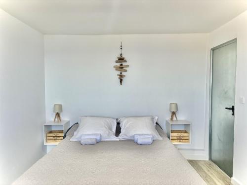 a white bedroom with a bed with two pillows at Residence Canella in Sari Solenzara