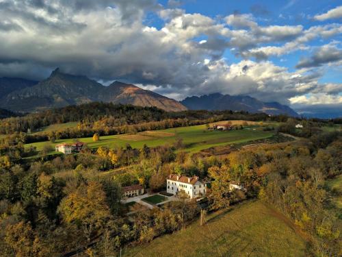 an aerial view of a house in a field with mountains at Villa San Liberale - Suites & Wellness - Villa Veneta in Feltre