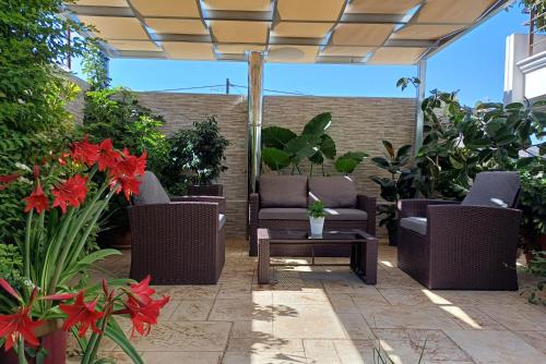 un patio con sillas, una mesa y flores en Melinta Stay - Near Airport, Rafina Port & Sea, en Artemida