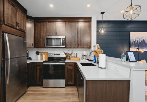 a kitchen with stainless steel appliances and wooden cabinets at The Loft on Gillis AC Downtown Beach Rooftop in Traverse City