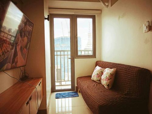 uma sala de estar com um sofá e uma grande janela em The ICONIC: Comfortable living by Awsom Phil em Manila