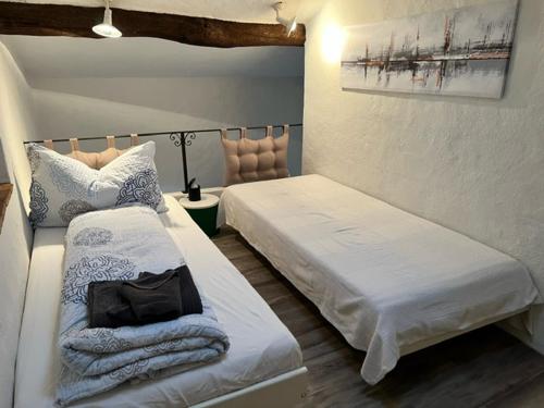 1 dormitorio con 2 camas y 1 silla en Caslano: 2.5 Zi-Dachwohnung im rustikalen-modernen Stil, en Caslano