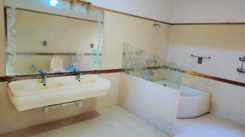 a bathroom with a sink and a tub and a toilet at Clifton Lodge Boutique Hotel in Karachi