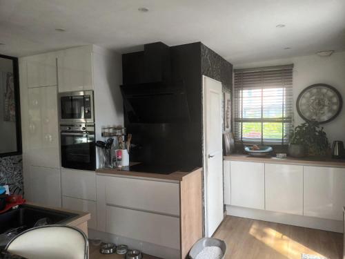 une cuisine avec des placards blancs et un mur noir dans l'établissement Grande maison familiale et cossue, à Fontaine-Étoupefour