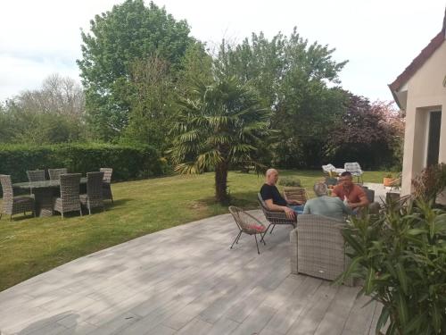 un groupe de personnes assises sur un patio dans l'établissement Grande maison familiale et cossue, à Fontaine-Étoupefour