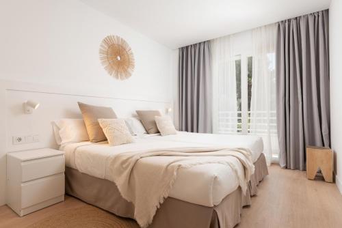 a white bedroom with a large bed and a window at Bauló Mar Apartments in Can Picafort