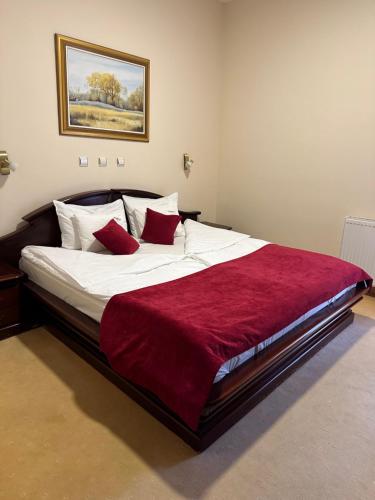 a bedroom with a large bed with a red blanket at Hotel Villa Majur in Subotica