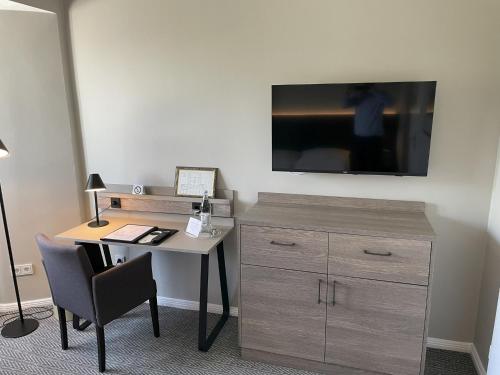 a desk with a dresser and a tv on a wall at Kurhaus Hotel in Wyk auf Föhr