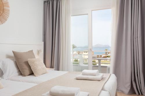 a white room with a bed and a large window at Bauló Mar Apartments in Can Picafort