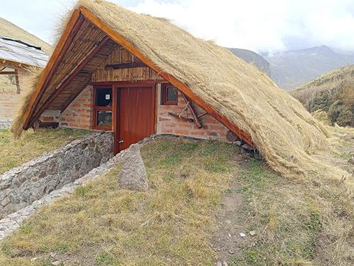 um pequeno edifício com um telhado de relva numa colina em Chimborazo Basecamp em Chimborazo