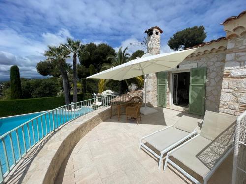 a patio with a table and umbrella next to a swimming pool at La Bergerie B&B in Vence