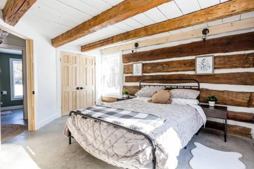 1 dormitorio con 1 cama y pared de madera en Cottontail Cabin with Hot Tub and wood fired Sauna en Merrickville