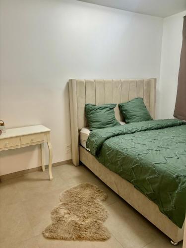 Cette chambre comprend un lit avec des draps verts et un bureau. dans l'établissement Apparemment au bord du lac,10 min de Paris,12 min de stade France, à Épinay-sur-Seine