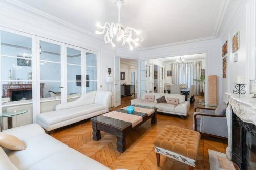 Elle comprend un salon doté d'un mobilier blanc et d'une cheminée. dans l'établissement Appartement fabuleux - 16eme, à Paris