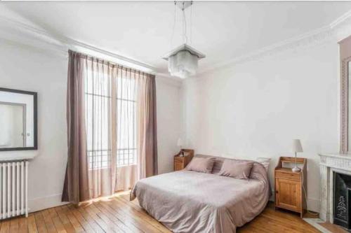 une chambre blanche avec un lit et une cheminée dans l'établissement Appartement fabuleux - 16eme, à Paris