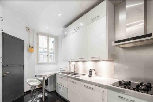 une cuisine blanche avec un évier et un plan de travail dans l'établissement Appartement fabuleux - 16eme, à Paris