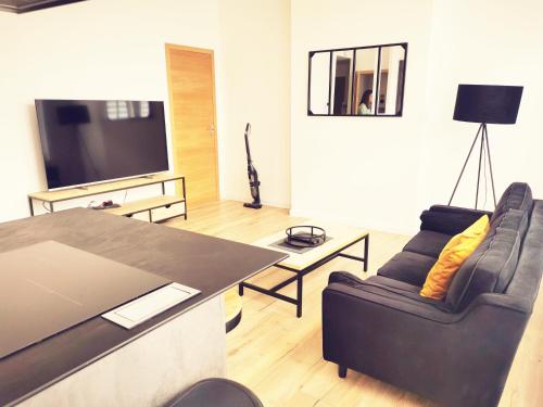 sala de estar con sofá, mesa y TV en Le moderne 100 mètres de la gare parking gratuit, en Douai