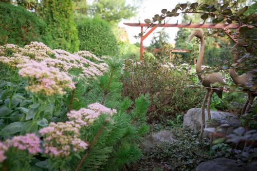 a garden with pink flowers and a bird statue at Green Park Villa in Eger