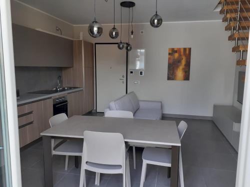 a kitchen with a white table and white chairs at Appartamento Scoggione in Colico