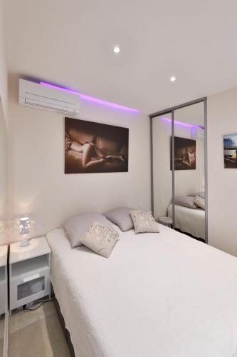 - une chambre blanche avec un lit blanc et un miroir dans l'établissement Appartement Naturiste de Standing 3* Heliopolis AB, au Cap d'Agde
