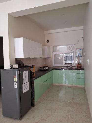 a kitchen with green and white cabinets and a refrigerator at 636 Kedia Kothhi in Jaipur